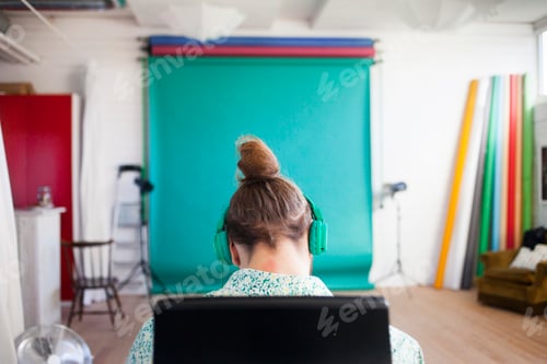Preview: A person with headphones focused on a computer screen in a creative studio environment.