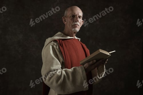 Preview: Official Portrait Of Monk Holding Book. Studio Shot Against Dark Wall.
