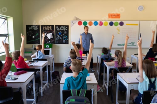 Preview: Male school teacher standing in an elementary school classroom with a group of school children