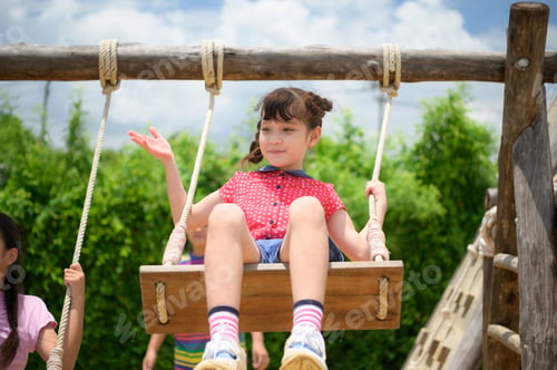 Preview: Childrens having fun swinging on a swing on a clear day