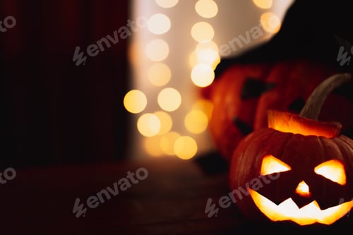 Preview: Pumpkins with evil carved faces on wooden table