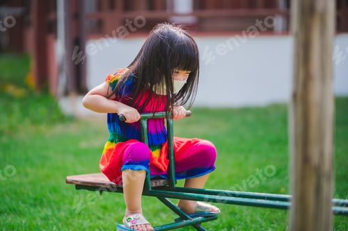 Preview: Child wearing mask is playing with downed horse. Girl played playground equipment.