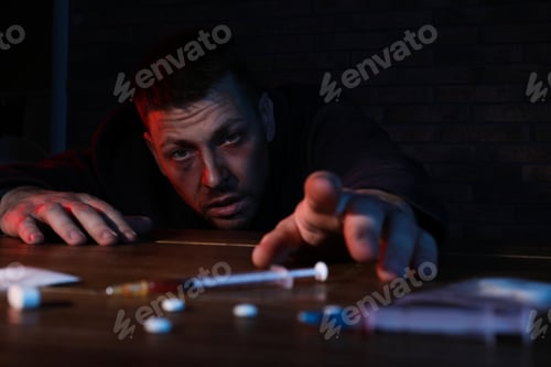 Preview: Addicted man reaching to drugs at table