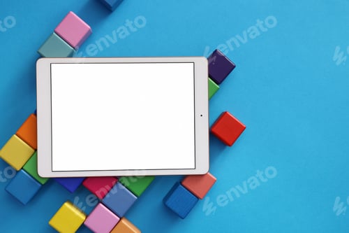 Preview: Modern tablet and cubes on light blue background, flat lay. Space for text