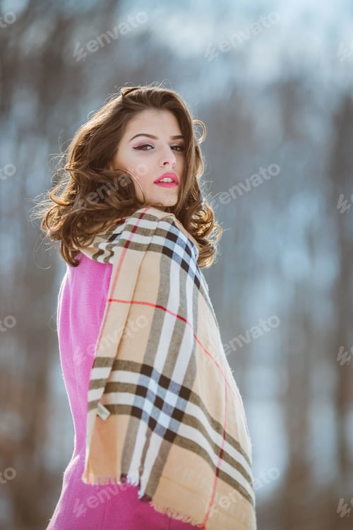 Preview: Vertical shallow focus shot of a female wearing a scarf and pink coat during winter