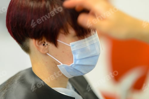 Preview: Closeup shot of a female getting her hair done wearing a face mask - concept of the new normal