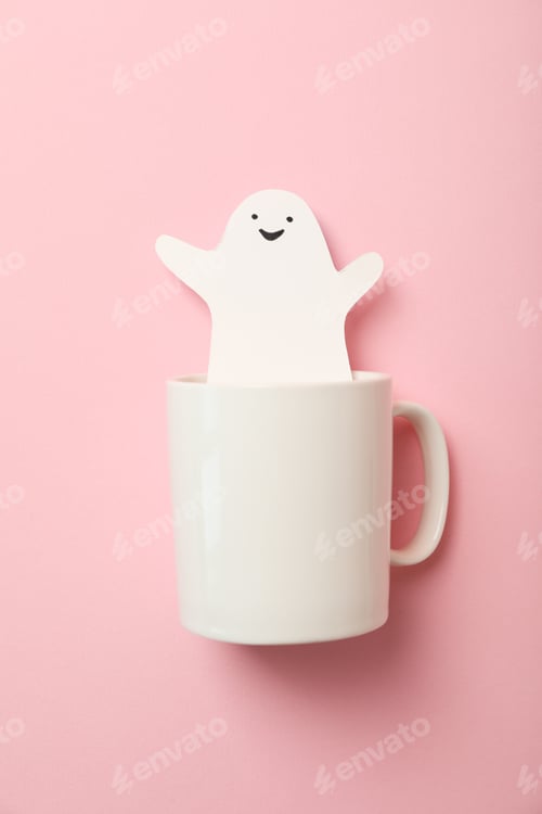 Preview: Paper ghost in cup on pink background, top view