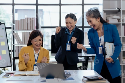 Preview: Excited asian business team celebrating victory together in office.