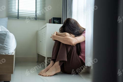 Preview: Asian young upset depressed woman sitting alone in living room at home.
