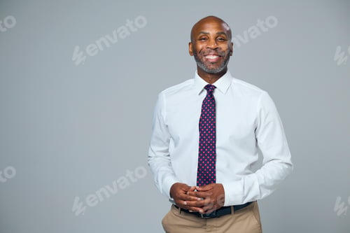Preview: Studio Portrait Of Smiling Mature Businessman Wearing Tie Against Grey Background