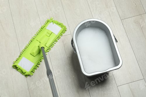 Preview: Microfiber mop and bucket with detergent on wooden floor, above view