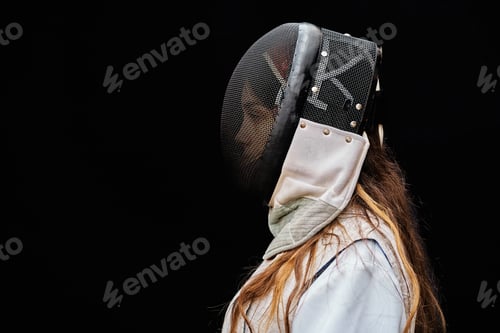 Preview: Portrait of woman dressed in white fencing costume practicing with the sword on black background.