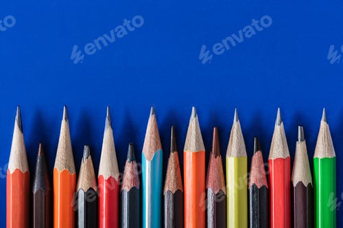 Preview: top view of colorful various pencils placed in row on blue background