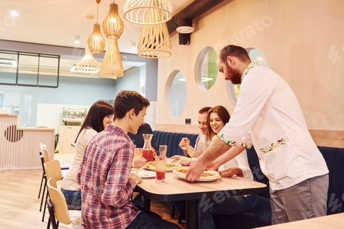 Preview: Chef delivers food. Group of young friends that sitting together indoors and eating pizza