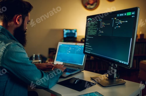 Preview: A full-stack senior developer is programming on a laptop from his home late at night.