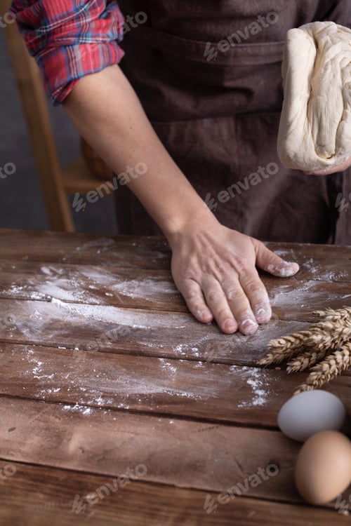 Preview: Baker male hand kneading dough and bakery ingredients for homemade bread cooking on table