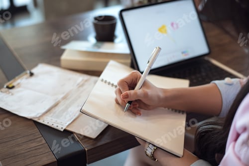 Preview: Close up. Woman taking notes on desk at cafe.