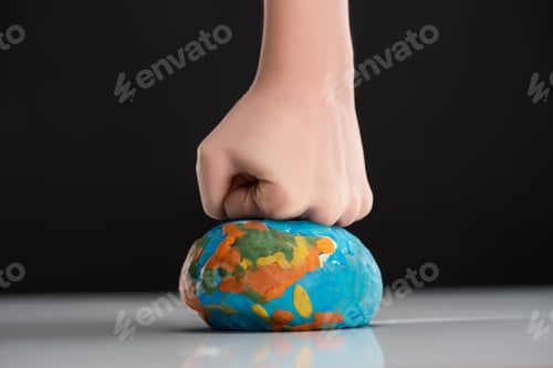 Preview: Partial view of woman compressing plasticine globe by fist isolated on black, global warming concept