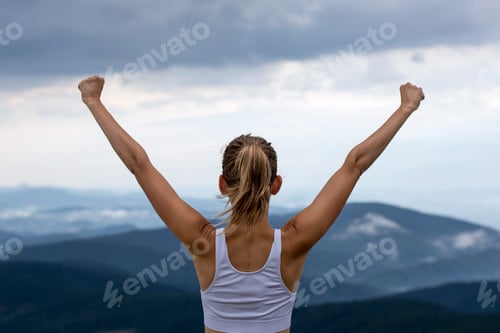 Preview: Young woman on top of the moutain with the arms raised enjoying freedom, Winner.