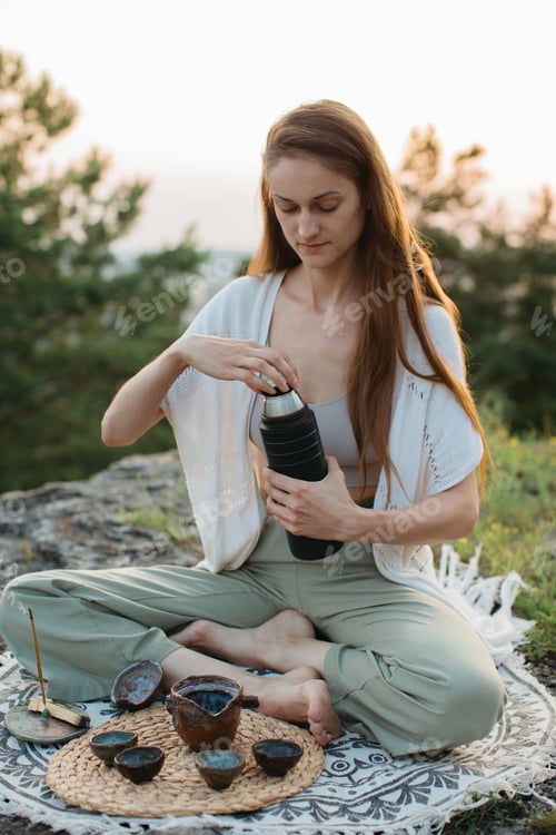 Preview: A young beautiful woman performs a Chinese tea ceremony in the mountains at sunset.