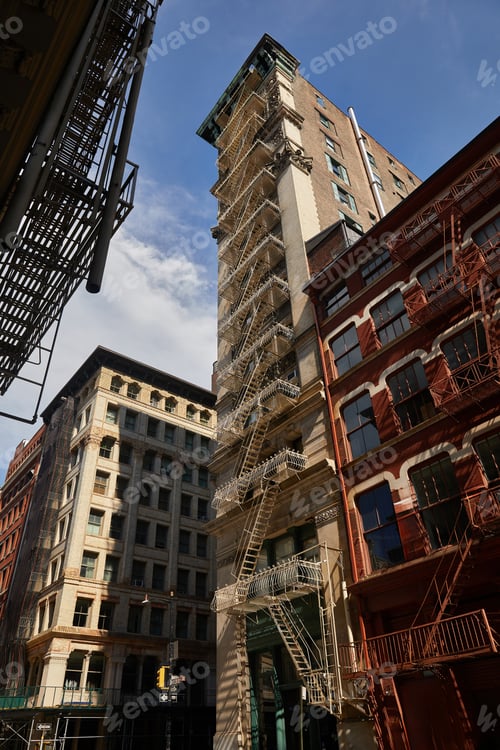 Vorschau: Blick aus dem niedrigen Winkel auf ein hohes Gebäude mit einer Feuertreppe an der Avenue im herbstlichen New York City