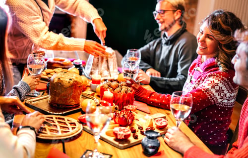 Preview: Happy young friends tasting Christmas sweet food having fun at home supper party