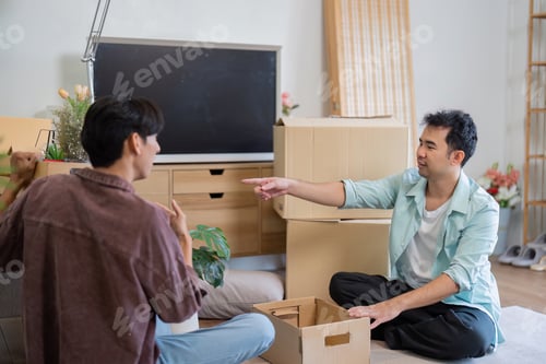 Preview: LGBT couple engaging in conversation while unpacking boxes in their new home