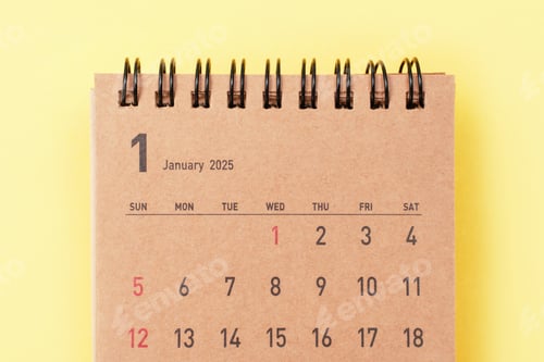 Preview: Brown calendar for January 2025 on yellow background close-up, planning concept.