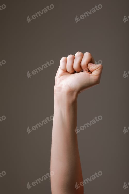 Preview: female hand clenched into a fist on a gray background.gesture of fighting, winning or protest.Human