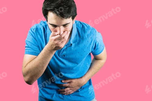 Preview: Young male holding his belly with one hand and the mouth with the other throwing up