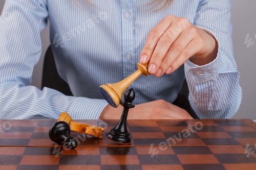 Preview: Young woman playing chess close up.