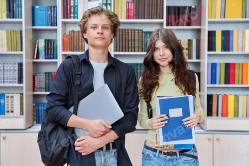 Preview: Portrait of two teenage students classmates, smiling guy and girl looking at camera in library