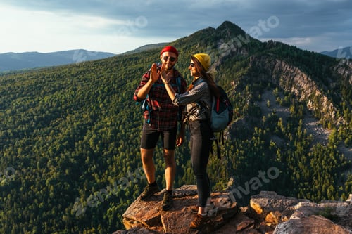 Preview: Adventurous Couple High-Fiving at Mountain Viewpoint