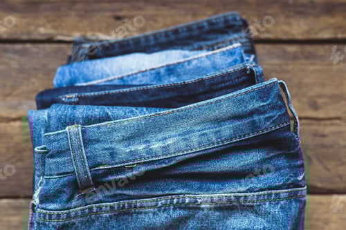 Preview: Pile of Stylish Blue Denim Jeans on Wood
