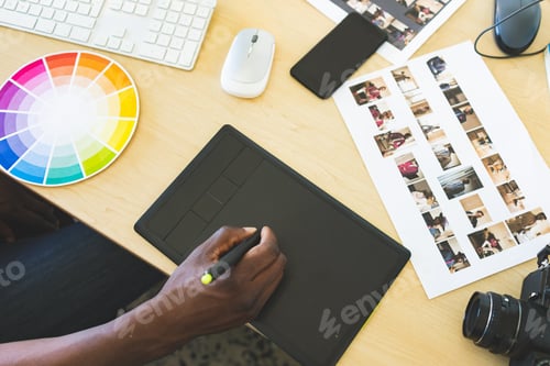 Preview: High angle view of young African-American businessman working on graphic tablet in office
