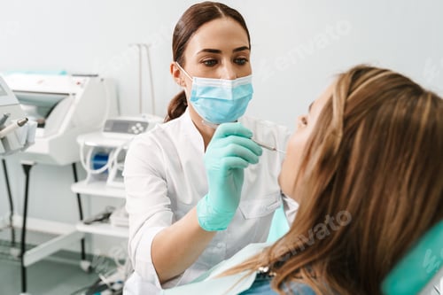 Preview: European mid dentist woman in face mask working in dental clinic