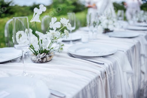 Preview: The festive table with a white tablecloth is decorated with flowers