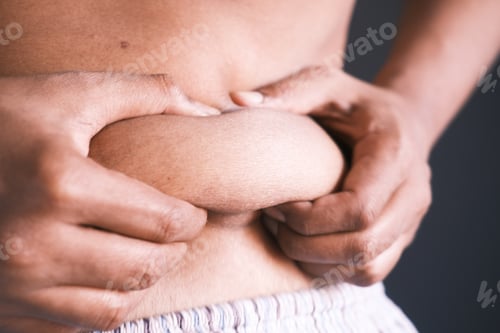 Preview: man's hand holding excessive belly fat, overweight concept