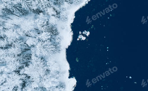 Preview: Aerial view of blue water sea and snow covered trees woods in winter Finland.