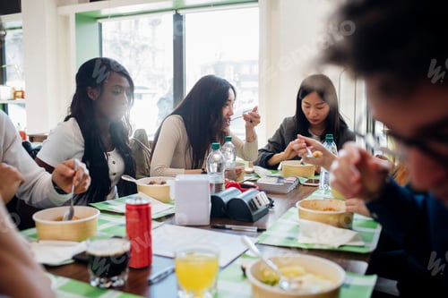 Preview: Young male and female business team sharing lunch in cafe