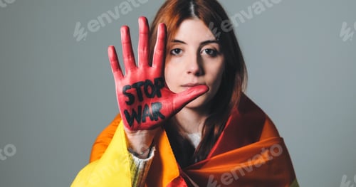 Preview: Girl wrapped in the peace flag raises her red hand that says stop war. Close-up shoot.