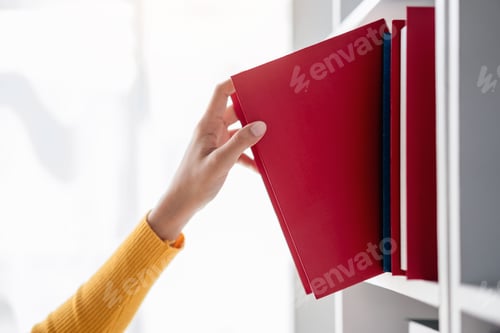 Preview: A person is reaching for a red book on a shelf