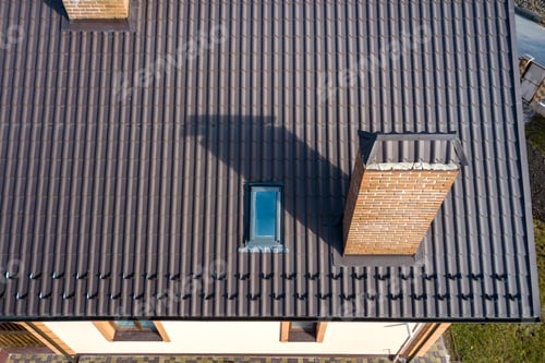 Preview: Aerial top view of building steep shingle roof, brick chimneys and small attic window on house top