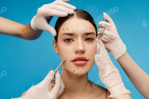 Preview: Surgeons in latex gloves touching face of pretty woman