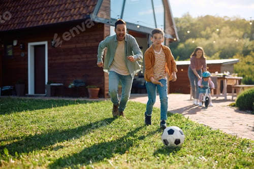 Preview: Happy father and son playing soccer in the backyard.