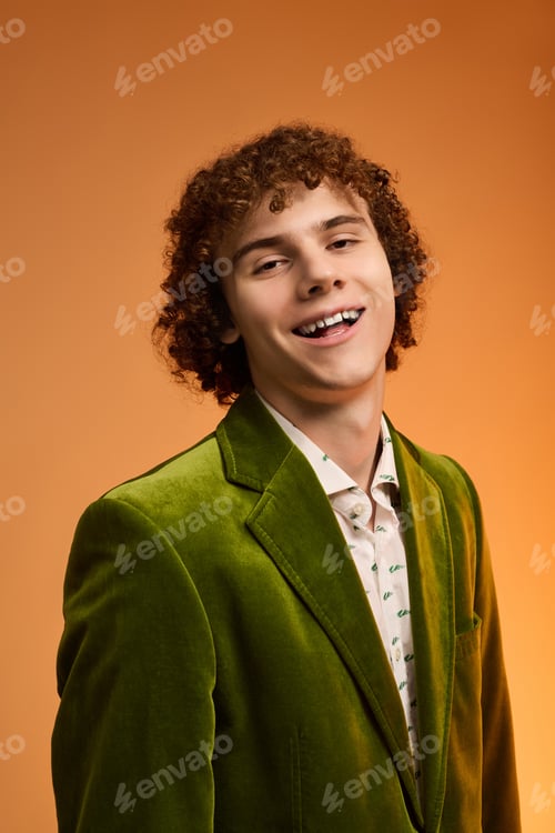 Preview: Curly teenage boy shines in vibrant green velvet blazer during studio shoot