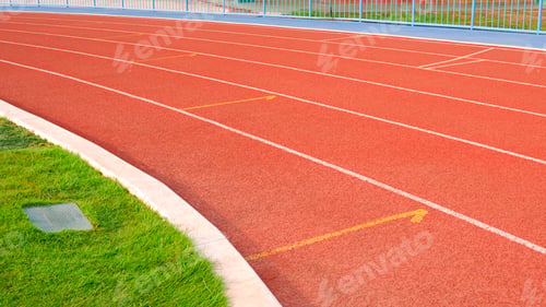 Preview: Empty red curve synthetic running tracks and green field in athletic outdoors stadium