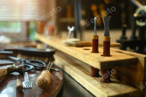 Preview: Various leather craft tools on wooden table in rustic workshop.