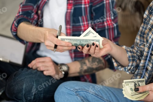 Preview: Young couple counting money while sitting on floor in new apartment.