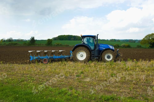 Preview: A tractor harrowing, ploughing in the stubble in a field.